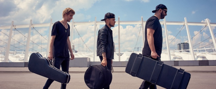 Three musicians carrying instruments about to board a bus